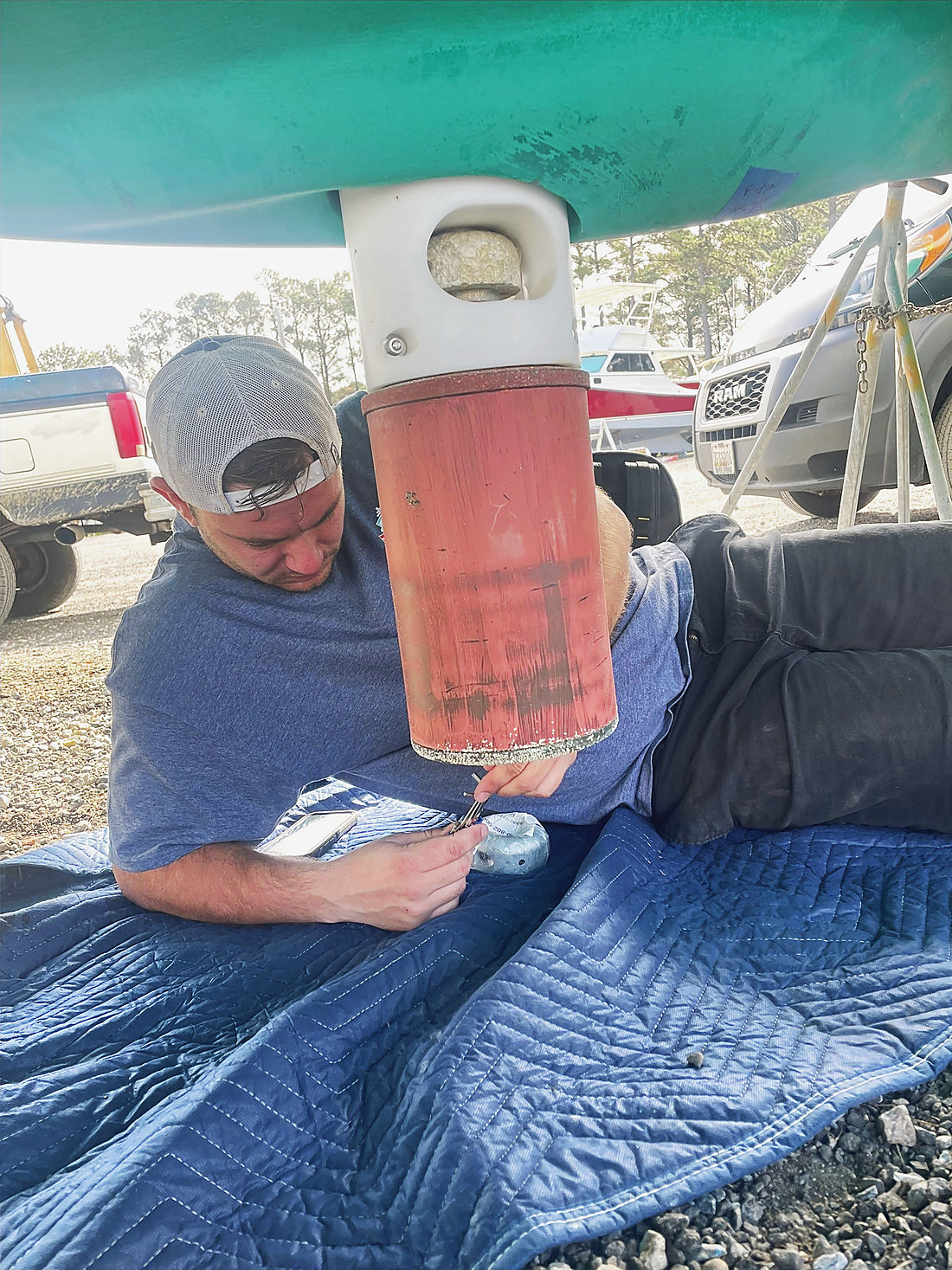 A technician working under a hull on the hard